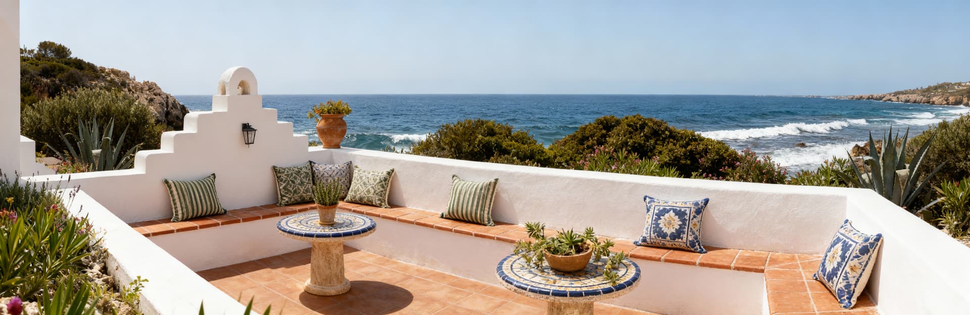Villa di lusso in Sardegna, affacciata sul mare, con facciata bianca e dettagli in cotto immersa nella macchia mediterranea.