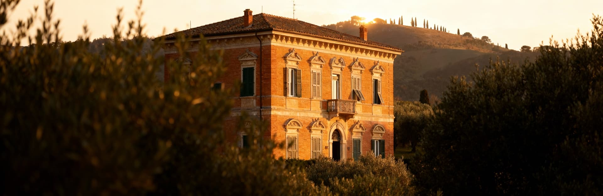 Vista di una storica villa a Lucca, in Toscana, circondata da uliveti e colline, illuminata dalla luce mattutina.