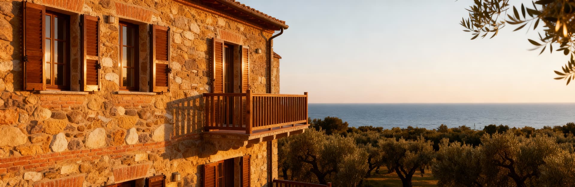 Agriturismo in vendita a Pisa, circondato da uliveti secolari e con vista mare, emerge in un paesaggio sereno e rustico.