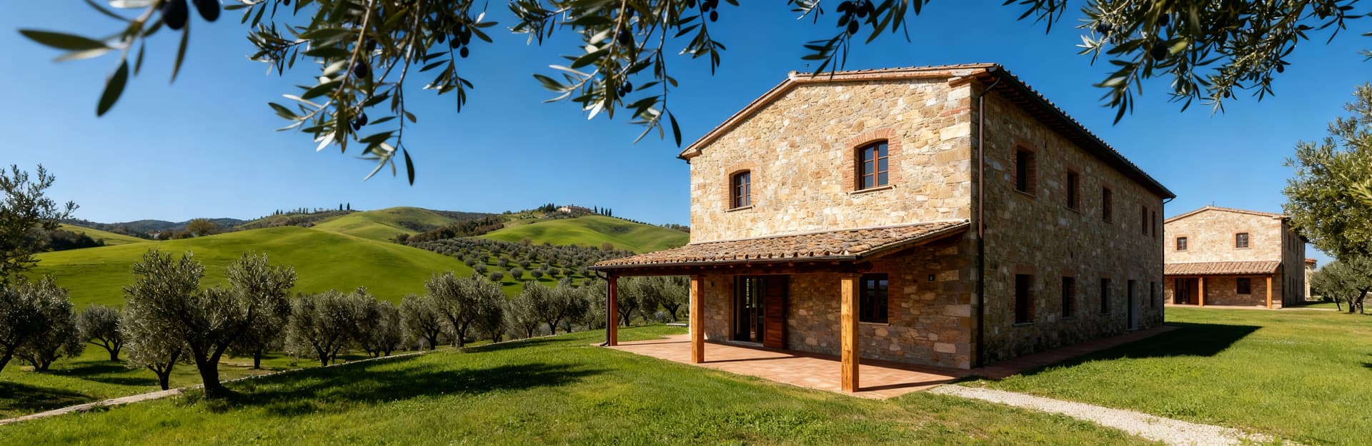 Casale in pietra immerso nel verde dell'Umbria, con uliveti e cielo sereno, rifugio ideale per il lusso rurale.