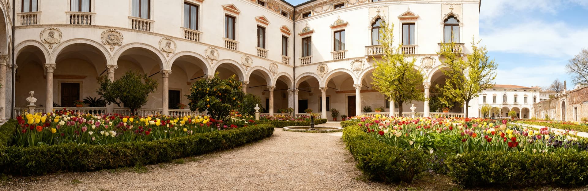 Palazzo storico a Treviso, facciate chiare e dettagli architettonici, cortile fiorito e cielo sereno in primavera.