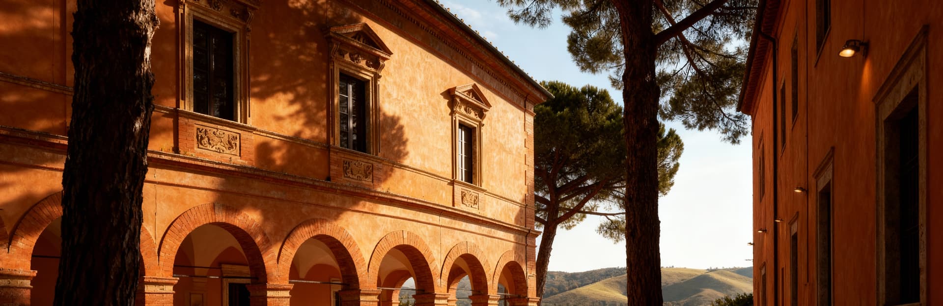 Palazzo storico a Grosseto, illuminato dal sole, con eleganti archi e finestre ornate, circondato da pini marittimi e colline toscane.