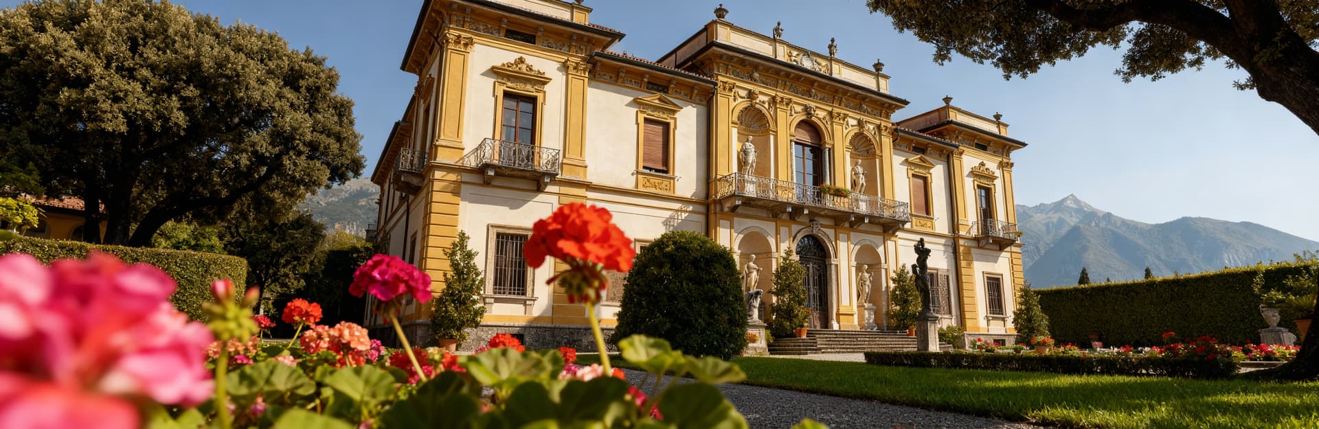 Villa storica a Como, circondata da giardini all'italiana, con panorama alpino e colori vividi sotto un cielo sereno.
