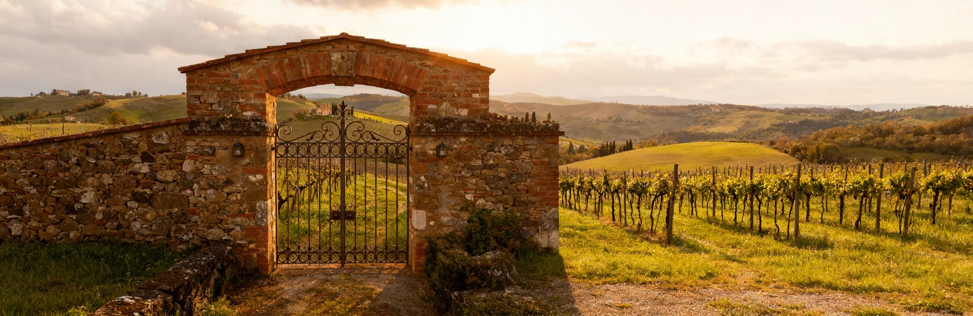 Villa storica in Val d'Orcia, architettura toscana tra colline e vigneti, cielo nuvoloso di primavera.