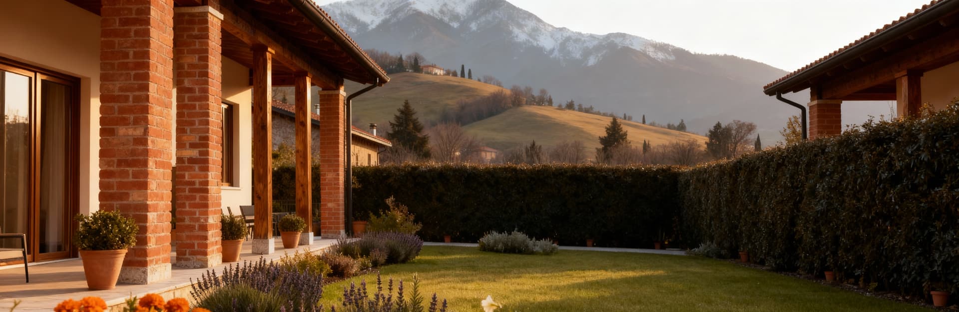 Elegante casale in mattoni a vista e legno, immerso in un giardino fiorito con colline bresciane sullo sfondo.
