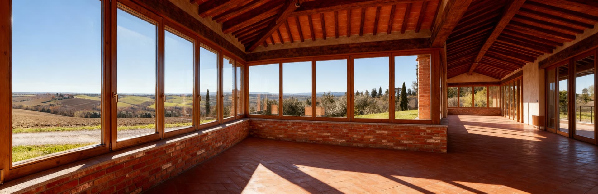 Elegante colonica in Emilia Romagna con ampie finestre che si affacciano sulla campagna, interni in legno e mattoni raffinati.