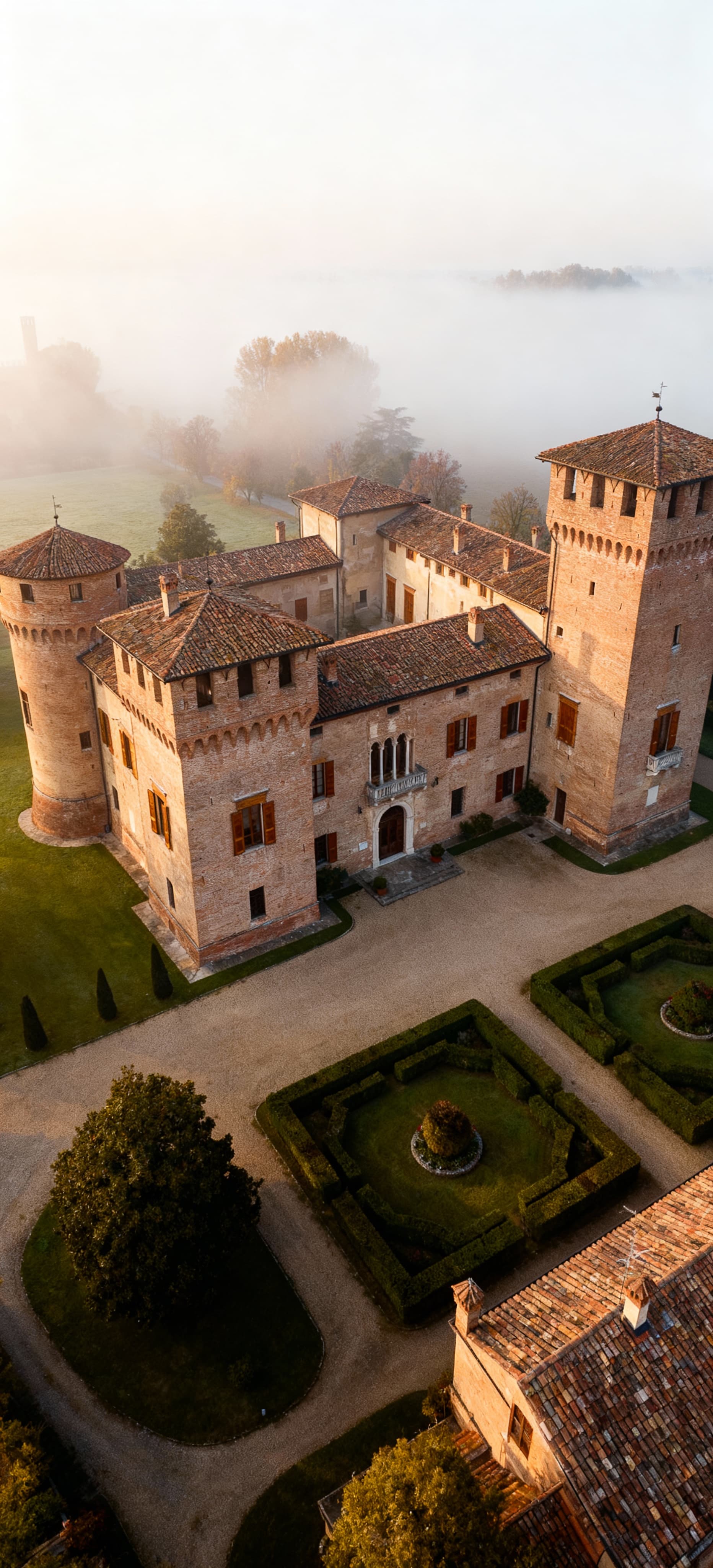 Castello storico a Lodi con giardino lussureggiante, avvolto da nebbia mattutina, esempio di architettura di lusso.