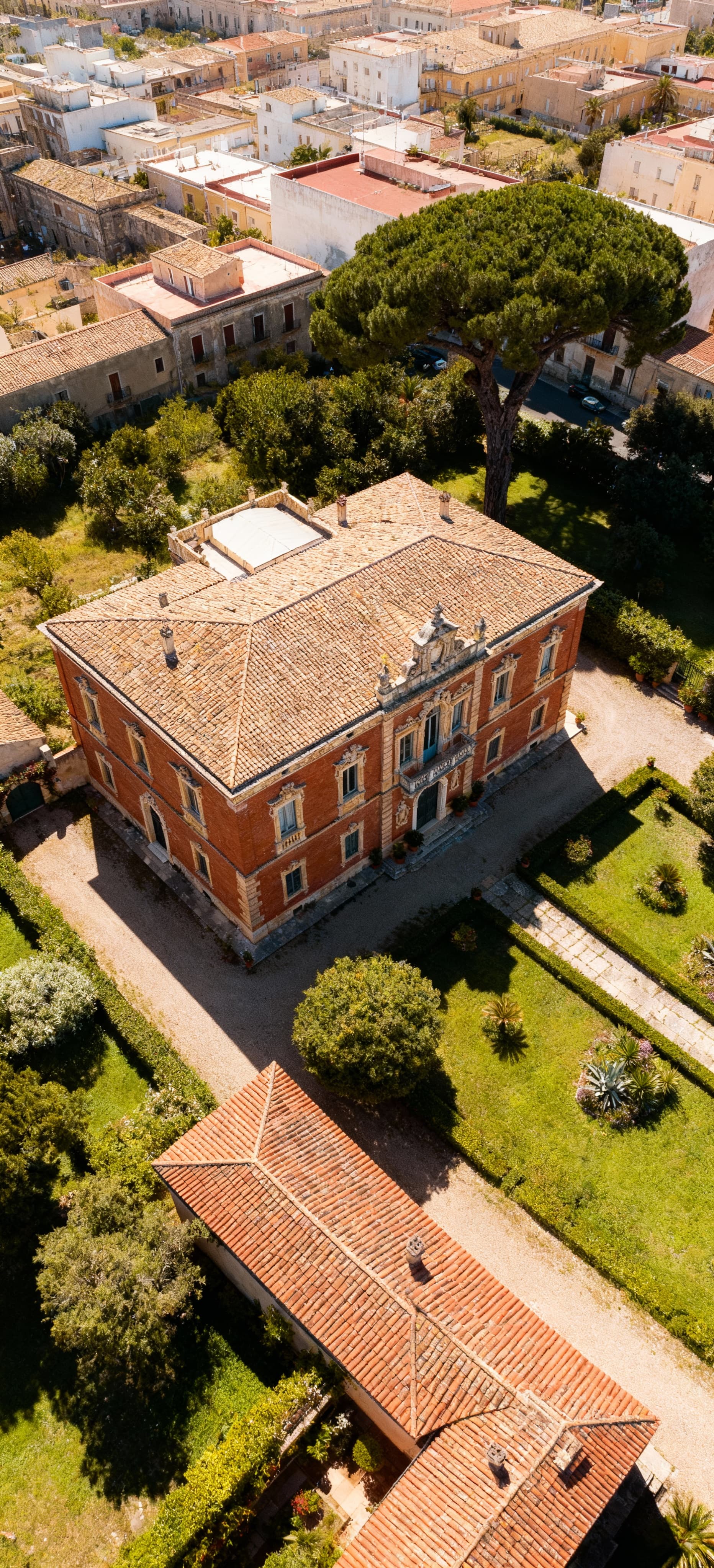 Villa storica a Sassari con architettura barocca, giardino curato e vista aerea sul contesto urbano circostante.