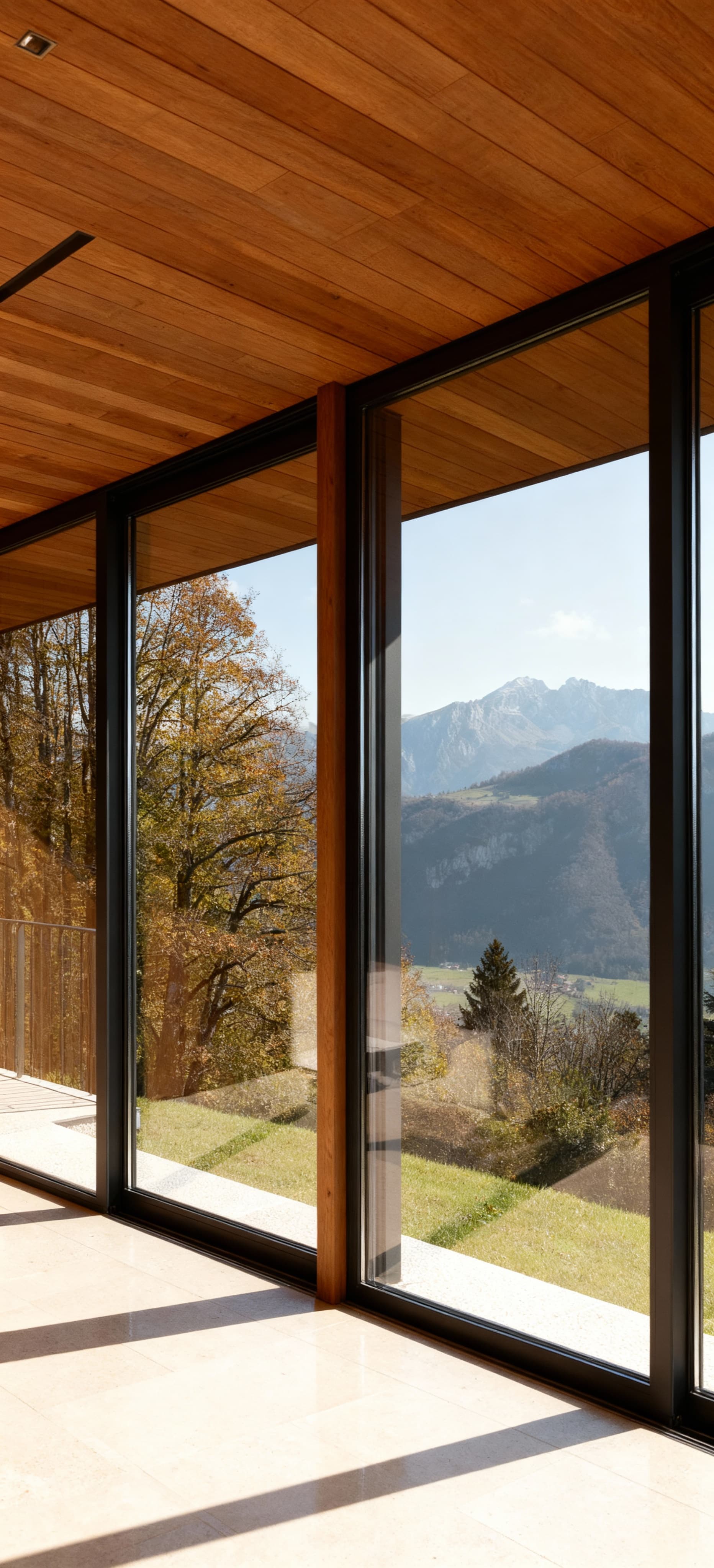 Villino moderno a Pordenone con ampie vetrate che si affacciano su un paesaggio montano, materiali legno e vetro.