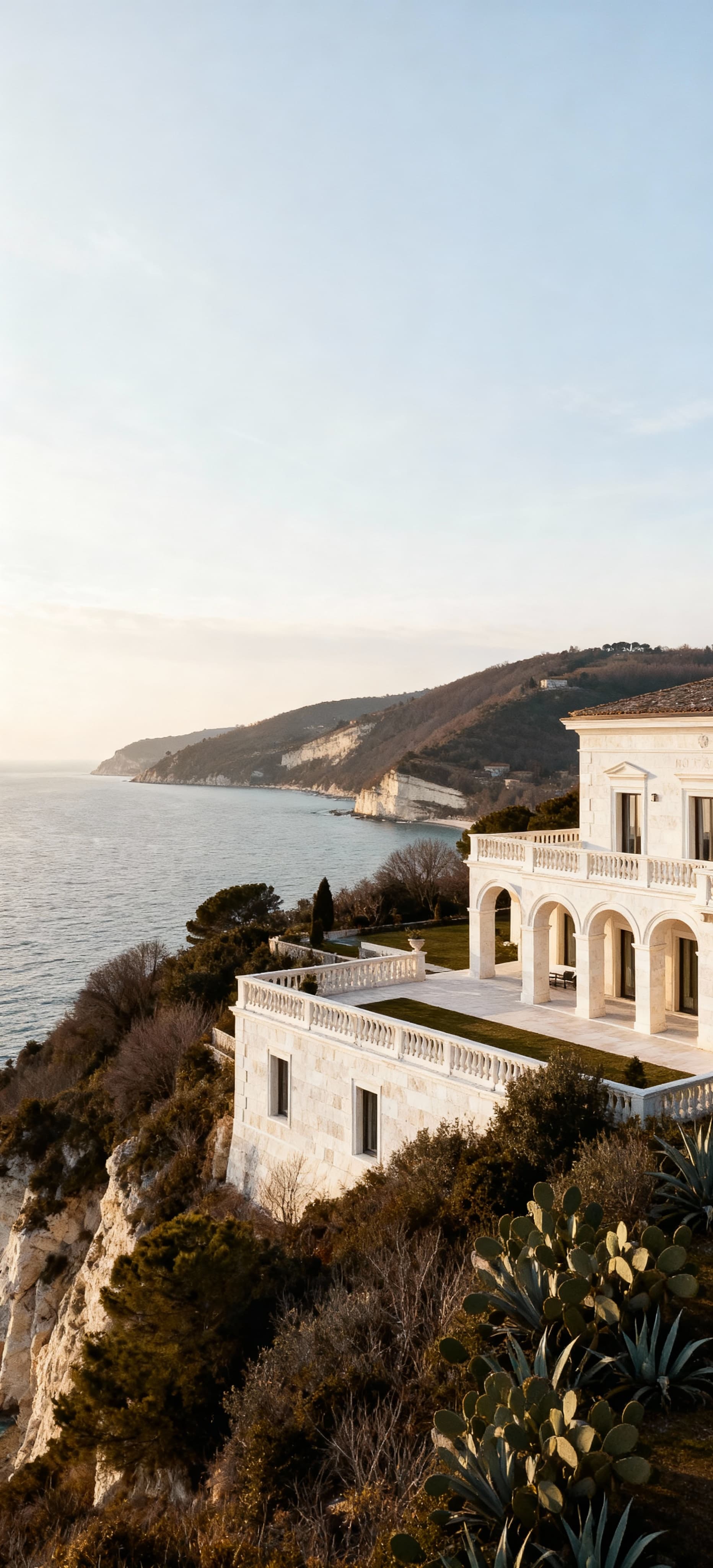 Elegante villa con vista mare ad Ancona, architettura in travertino bianco, illuminata da dolce luce invernale.