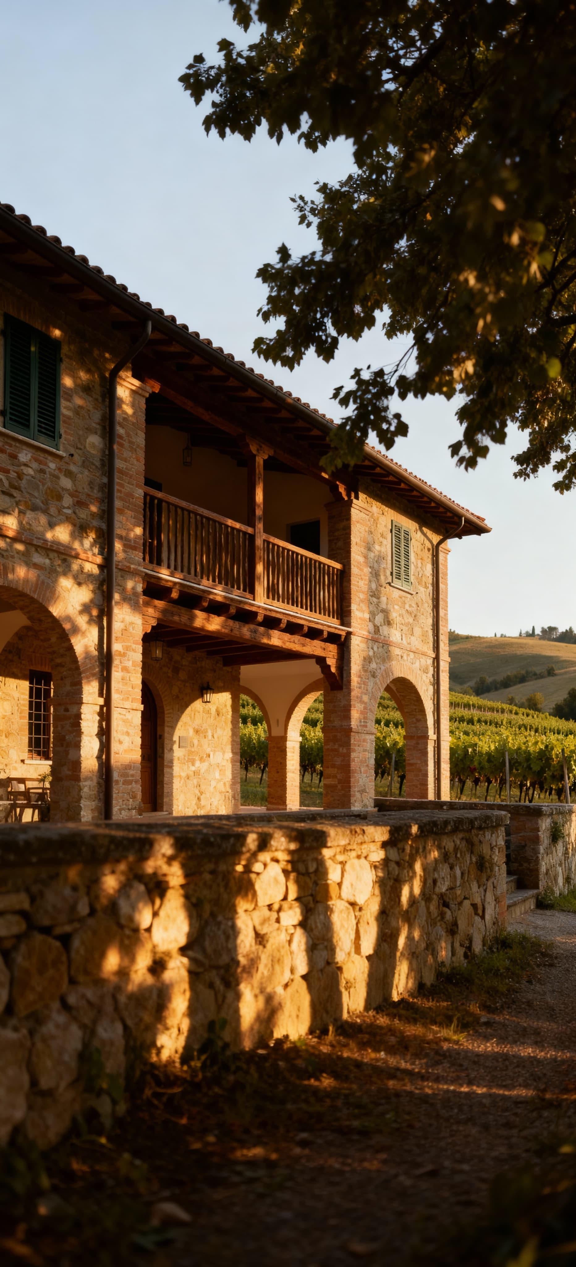 Villa storica in pietra tra colline dell'Emilia Romagna, con dettagli in legno e vigneto, evoca bellezza e tranquillità.