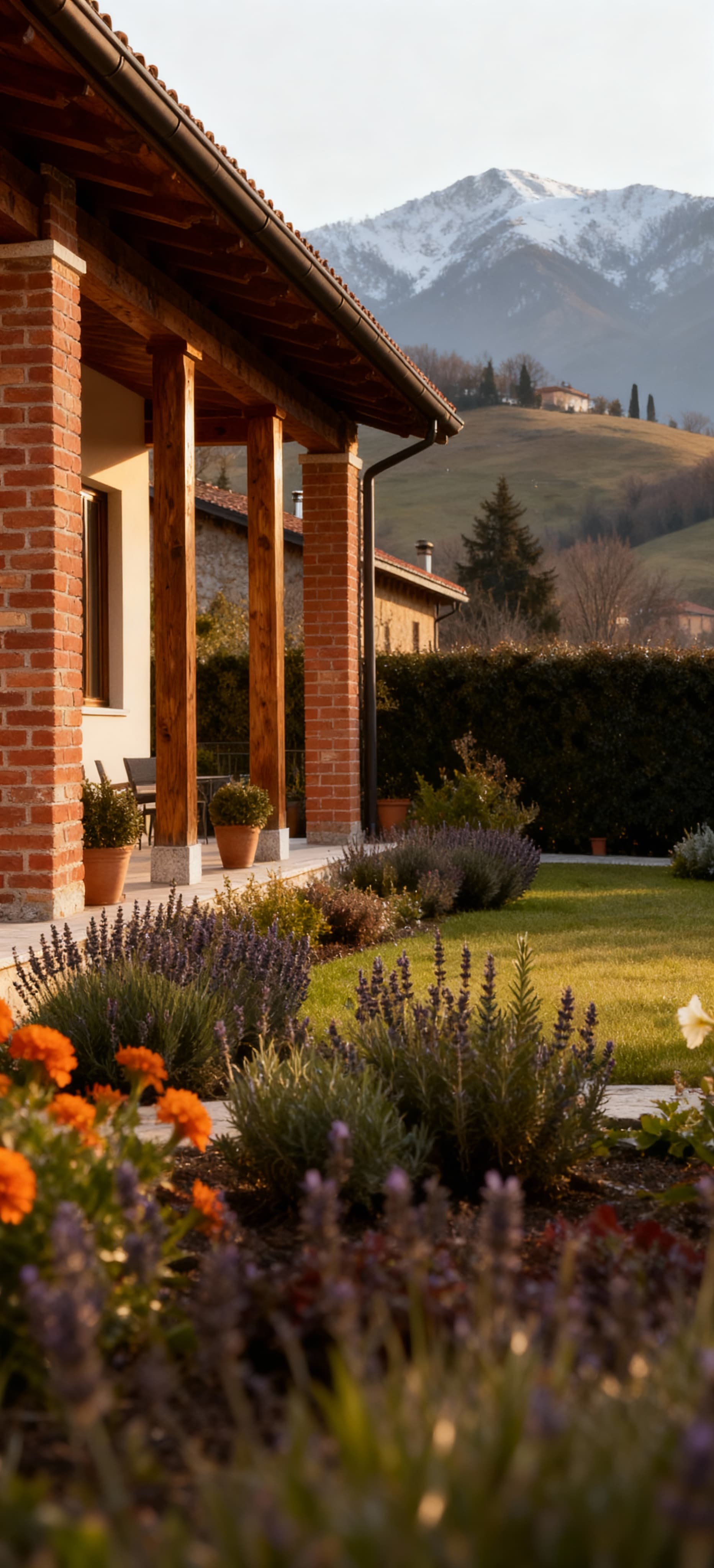 Elegante casale in mattoni a vista e legno, immerso in un giardino fiorito con colline bresciane sullo sfondo.