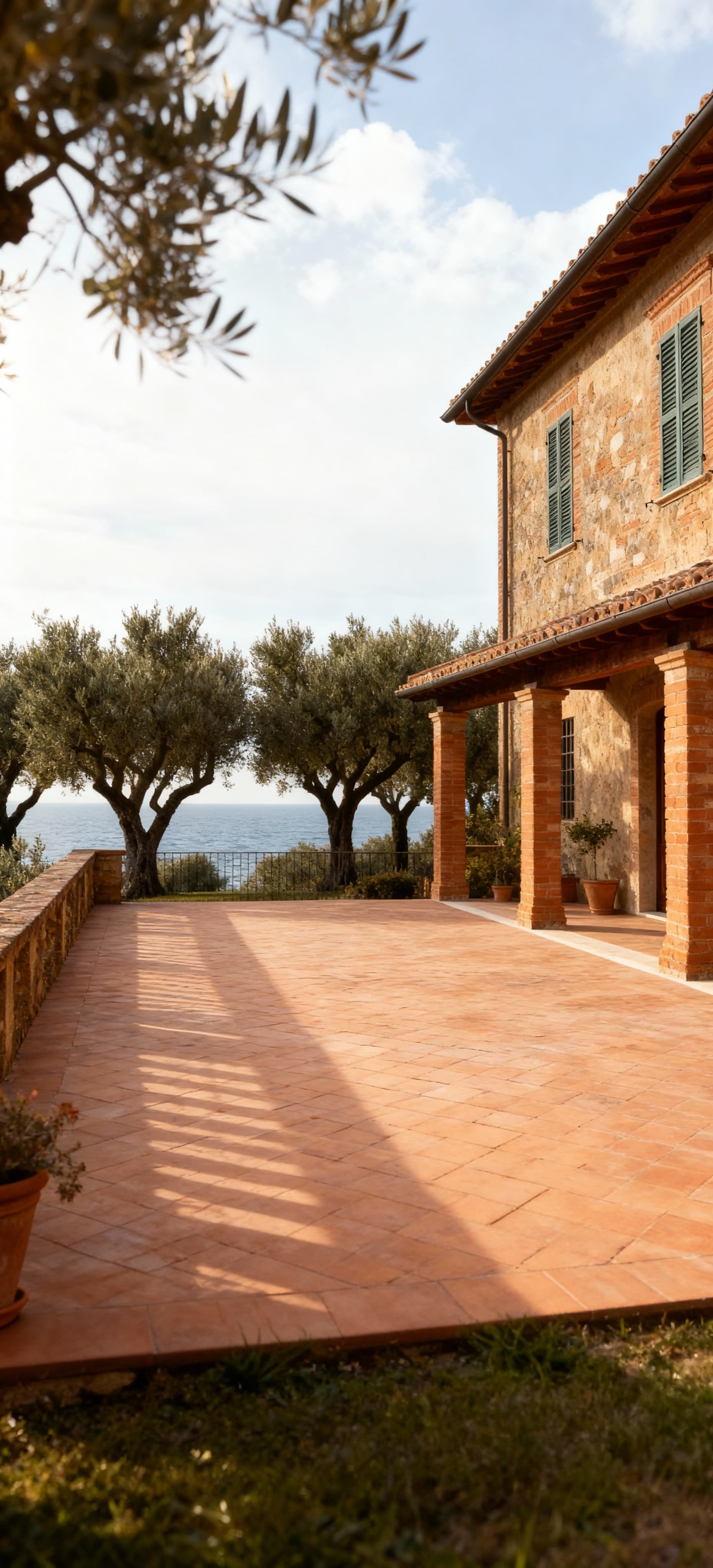 Rustico toscano con terrazza panoramica su uliveti, facciata in cotto e luce invernale, atmosfera calda e tranquilla.