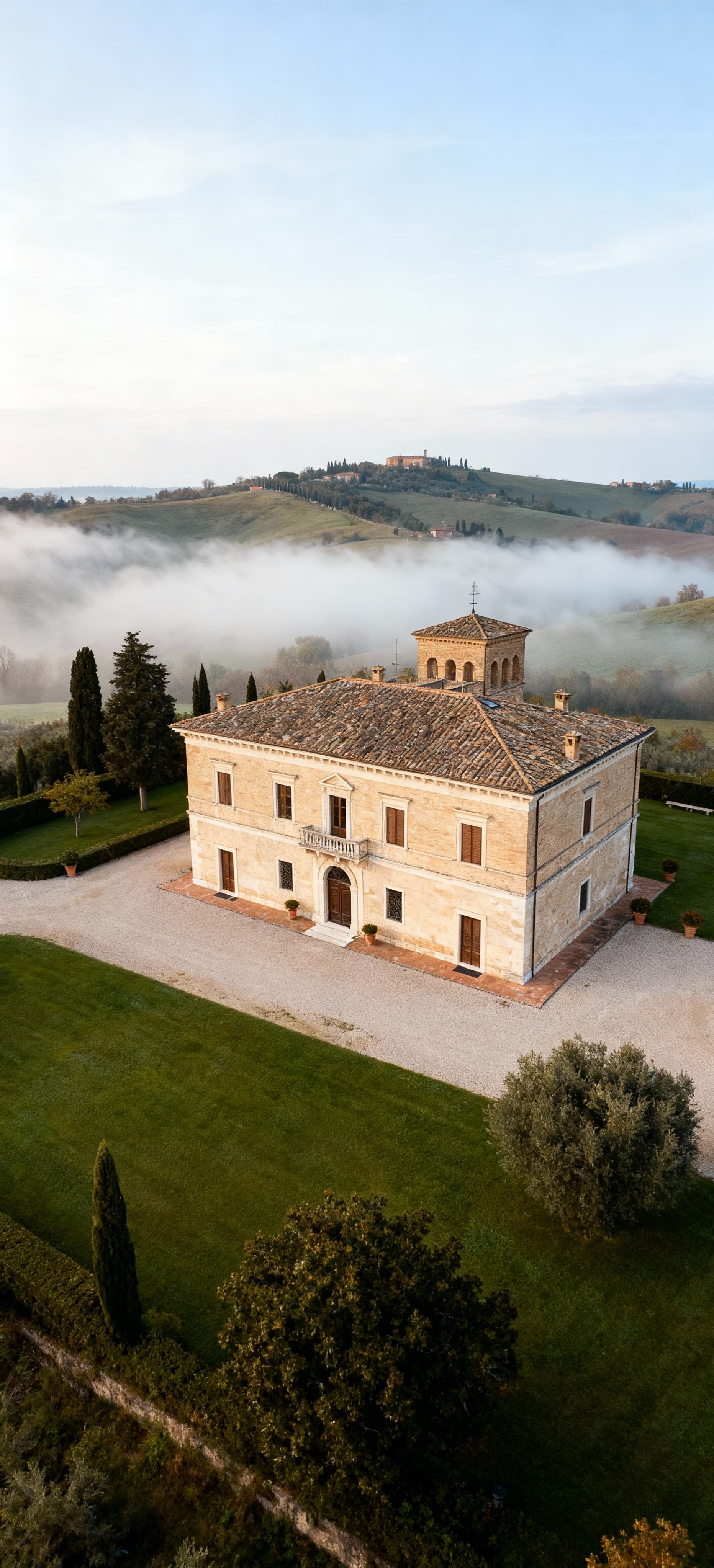 Villa storica a Fermo con giardino, vista panoramica su colline nebbiose, tipica architettura marchigiana, atmosfera serena.