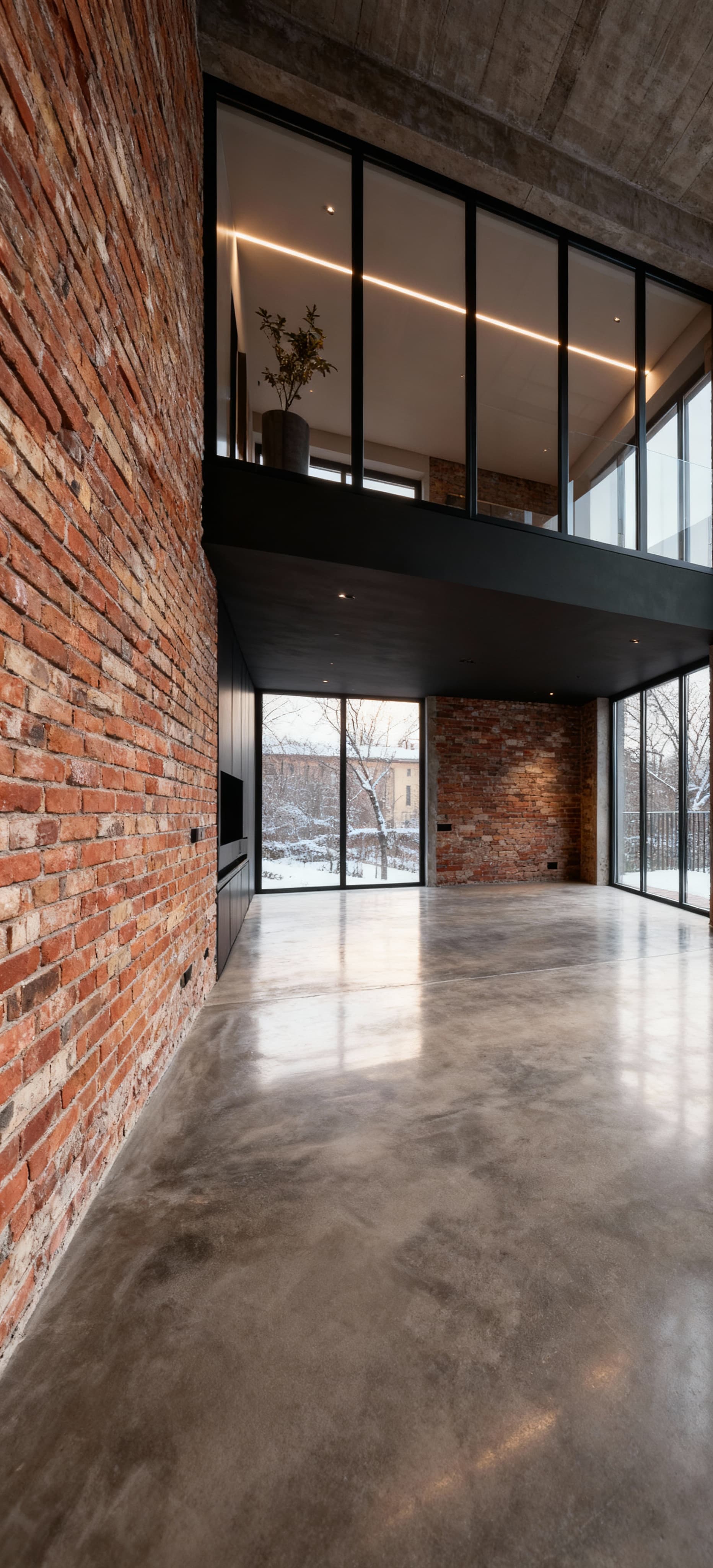 Loft open space in vendita con ampie vetrate, pavimenti in cemento e pareti in mattoni, illuminato da luce invernale.