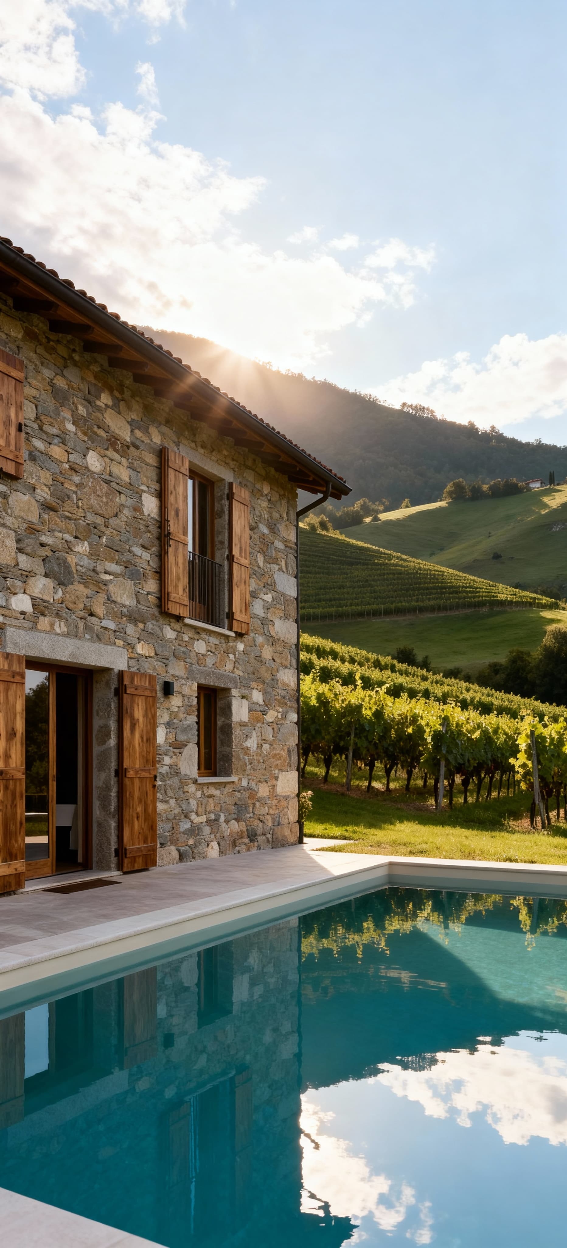 Casale ristrutturato a Cuneo, circondato da colline verdi e vigneti, con piscina e facciata in pietra locale.