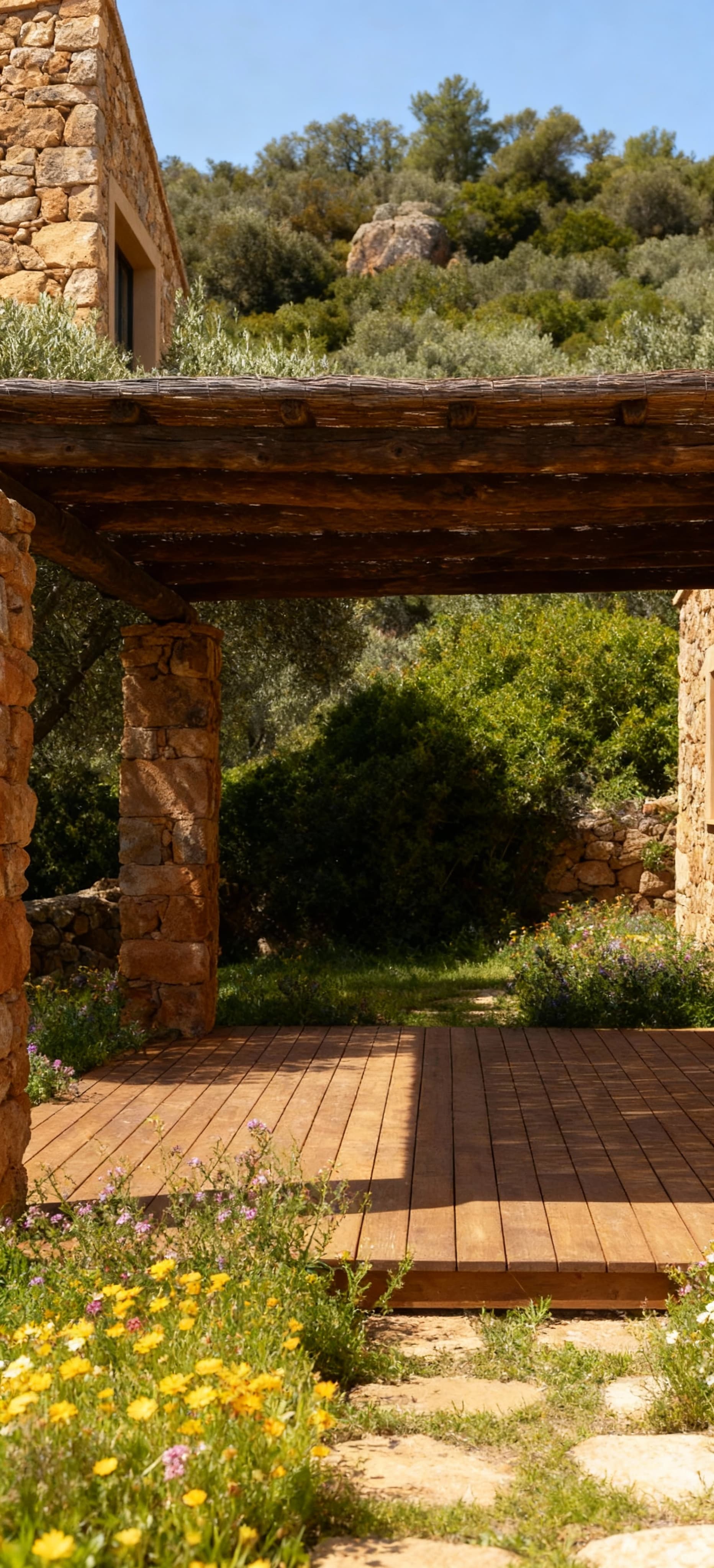 Rustico in pietra a Porto Cervo, circondato da uliveti e macchia mediterranea, con terrazza in legno e fiori selvatici.