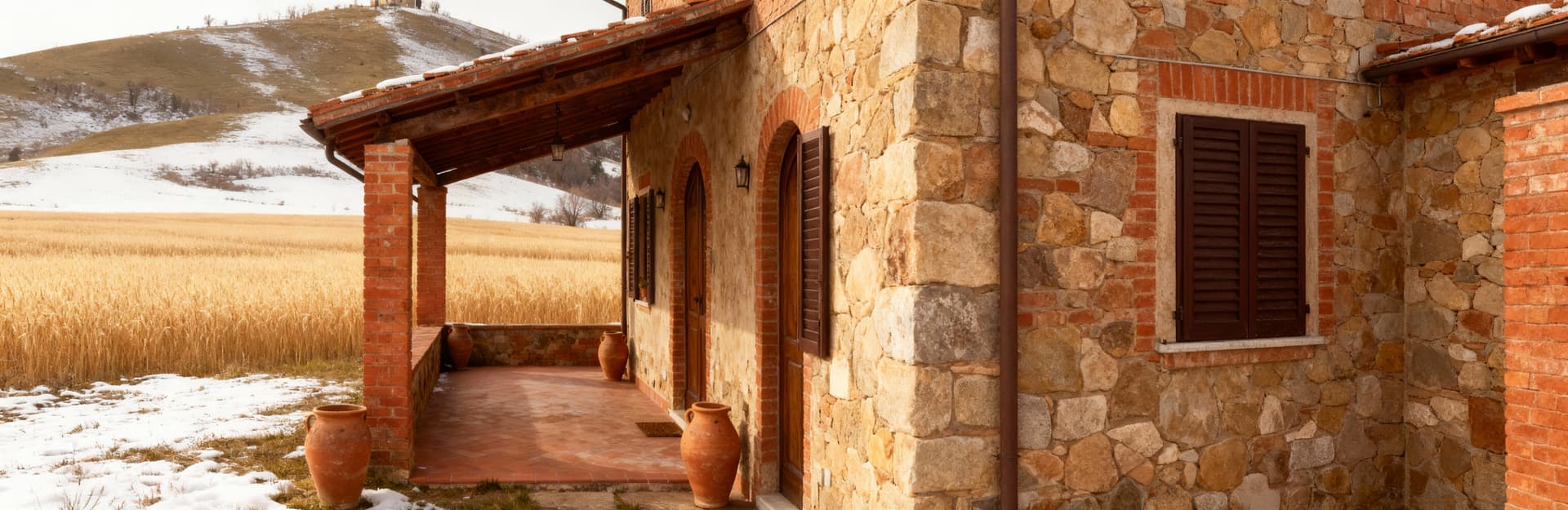 Rustico tradizionale in vendita in provincia di Forlì-Cesena, con mattoni rossi e portico affacciato su un campo dorato.