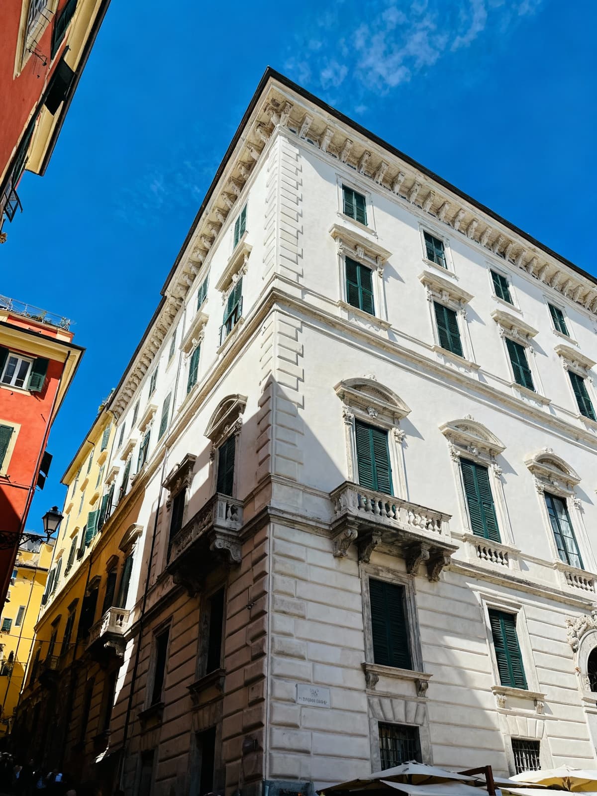 Elegant residences and historic buildings in the lively heart of Genoa, showcasing vibrant colors and stunning architecture under a blue sky.